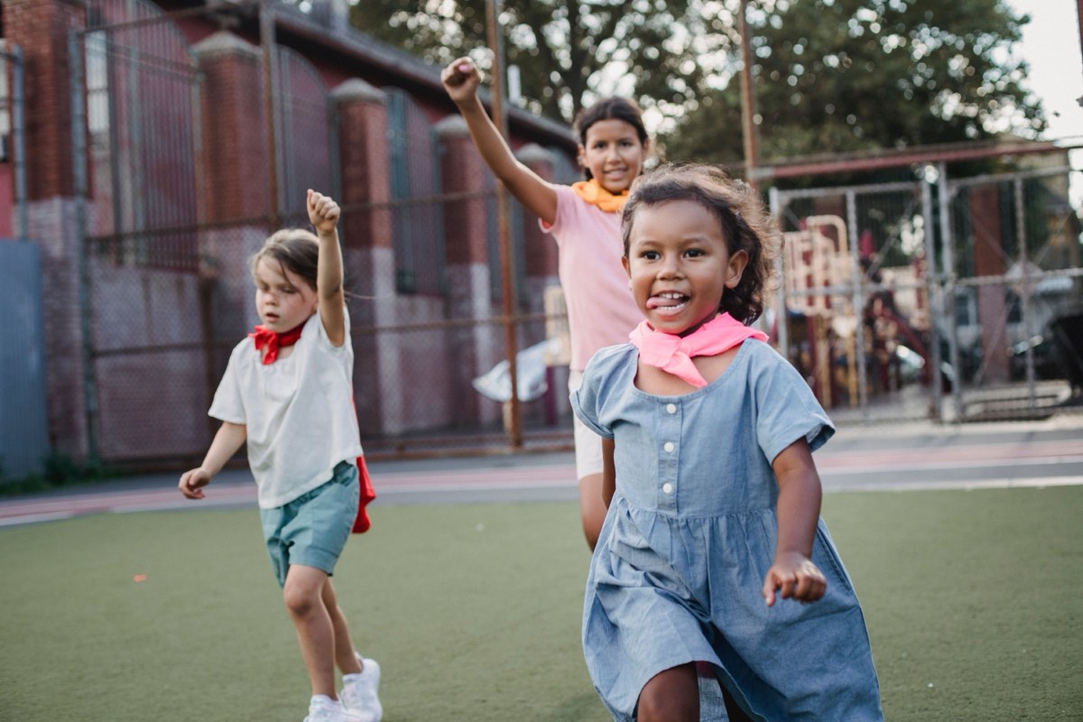 Young campers in capes running and laughing on a playground