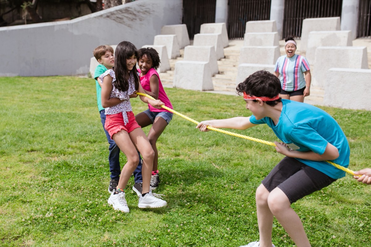 A group of campers playing tug of war on a lawn